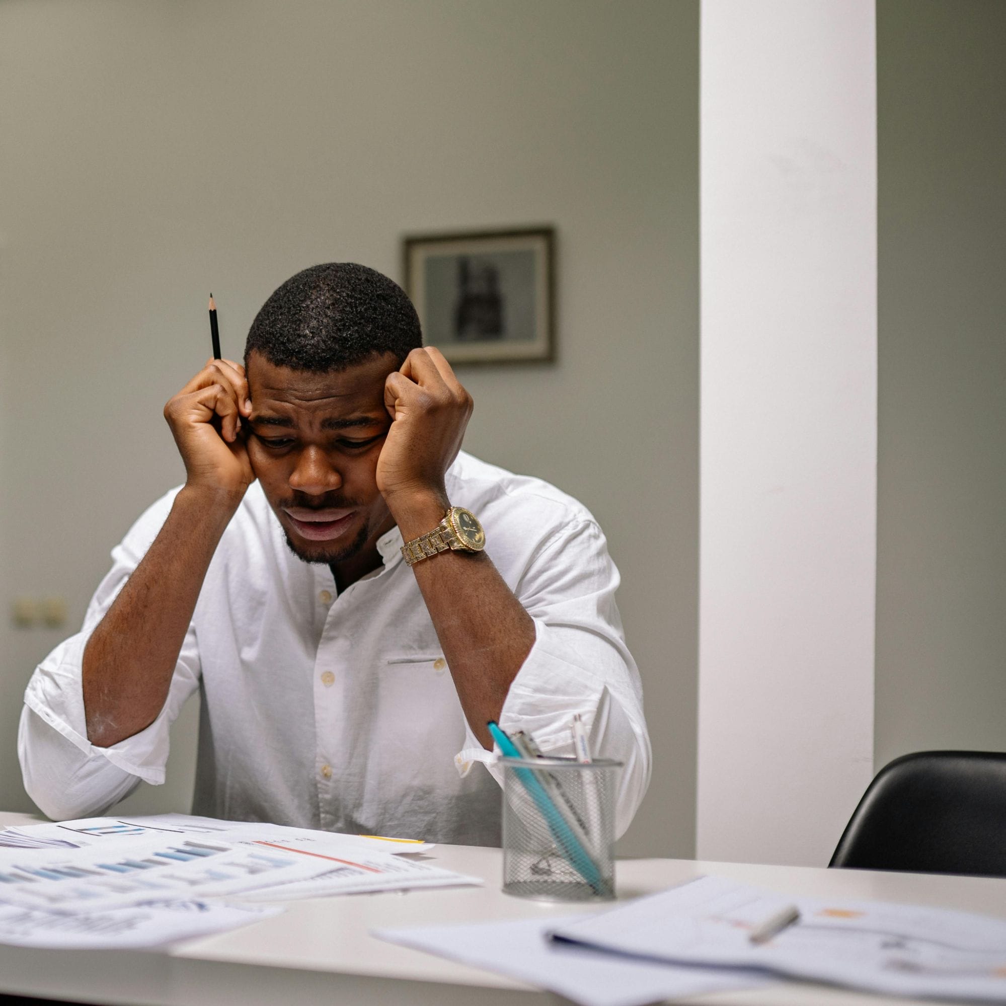 Business professional reviewing documents with hands on head at a desk