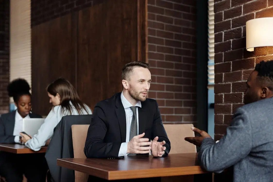Two professionals having a business discussion in a modern office setting, representing thought leadership and strategic conversation